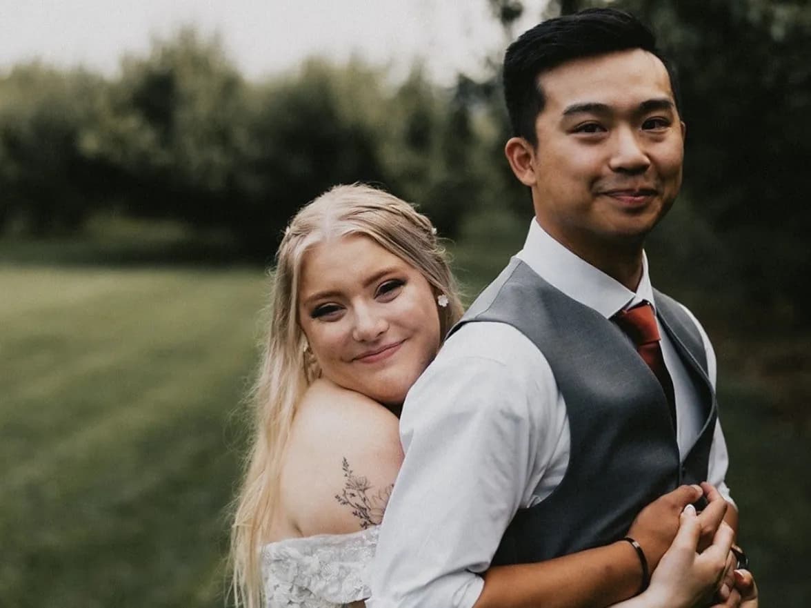 Branden and Sabrina on their wedding day, in a green orchard